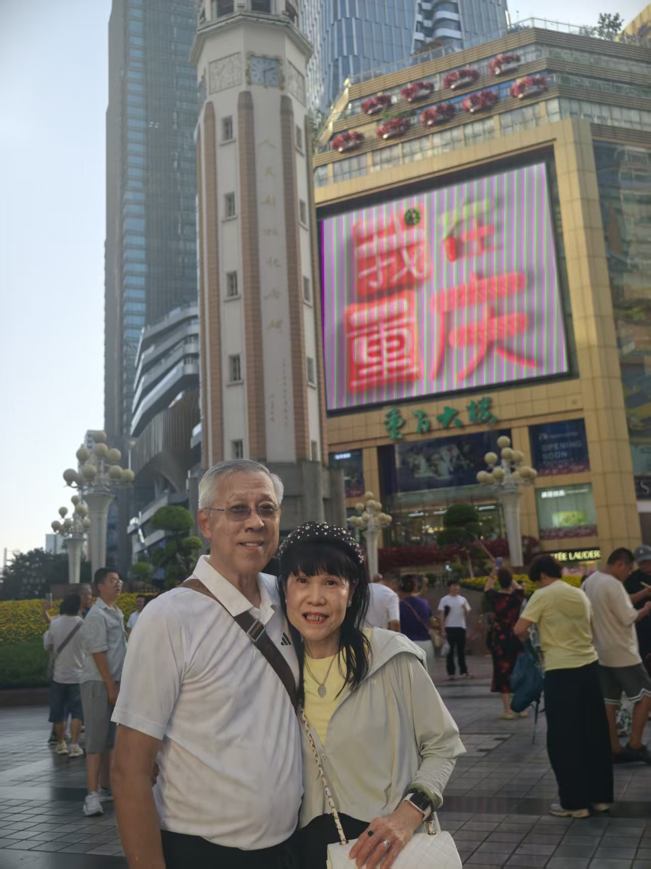 Pareja de clientes de 71Asia Tours frente a las pantallas del Jiefangbei de noche, en un itinerario privado por Chongqing